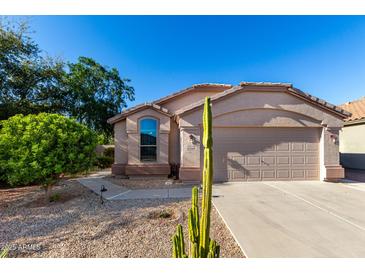 Charming single-story home with a two-car garage, desert landscaping, and a sunny blue sky at 42568 W Bunker Dr, Maricopa, AZ 85138
