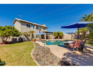 Inviting backyard featuring a sparkling pool, patio area, and lush landscaping under a blue sky at 7053 S Heather Dr, Tempe, AZ 85283