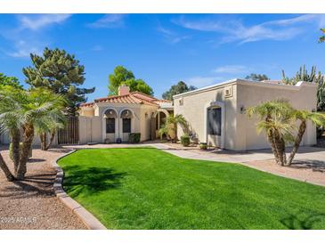 Charming single-story home with a lush green lawn, mature trees, and appealing desert landscaping at 7168 N Via De Amigos --, Scottsdale, AZ 85258