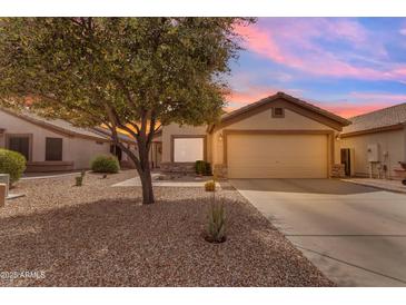 Charming single-story home featuring a two-car garage, desert landscaping, and a mature shade tree at sunset at 1285 E Cottonwood Rd, San Tan Valley, AZ 85140