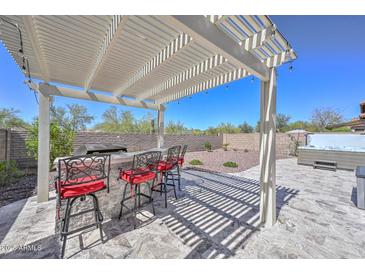 Outdoor kitchen with a built-in grill, bar seating, and shade from a covered patio at 29674 N 127Th Ln, Peoria, AZ 85383