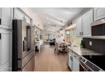 Bright, open kitchen with white cabinets, stainless steel appliances, and views of the dining and living areas at 8807 E Dahlia Dr, Scottsdale, AZ 85260