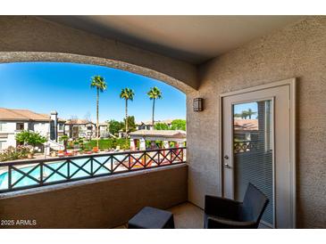 Relaxing balcony view of a community pool and palm trees, with comfortable seating at 1941 S Pierpont Dr # 2141, Mesa, AZ 85206