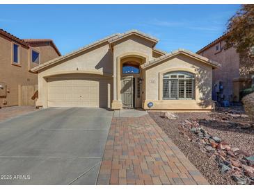 Single-story home featuring a two-car garage, desert landscaping, and a brick walkway to the front door at 2414 W White Feather Ln, Phoenix, AZ 85085