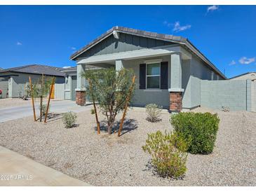 Charming single-story home featuring desert landscaping, a covered porch, and a neutral color palette at 24552 W Hilton Ave, Buckeye, AZ 85326