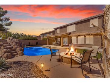 Stunning backyard with a pool, rock waterfall, and cozy fire pit with seating area at 45539 W Long Way, Maricopa, AZ 85139