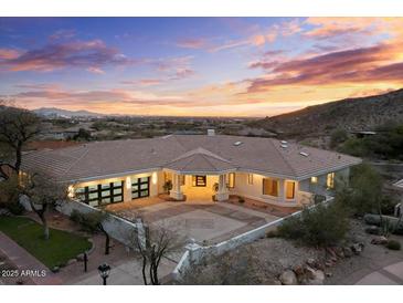 Expansive, modern home featuring large garage doors, a tile roof, and a circular driveway against a sunset backdrop at 6602 N Arizona Biltmore Cir, Phoenix, AZ 85016