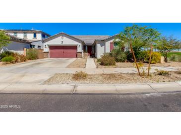 Charming single-story home with a red garage door, neutral stucco, and desert landscaping under a clear blue sky at 14188 W Artemisa Ave, Surprise, AZ 85387