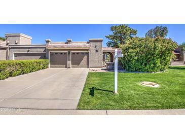 Charming single-story home featuring a well-manicured lawn, mature landscaping, and a two-car garage at 25273 S Berry Brook Dr, Sun Lakes, AZ 85248