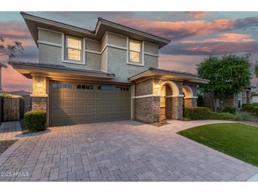 Charming two-story home featuring a stone-accented entrance, wide driveway, and a well-maintained lawn at twilight at 11544 W Ashby Dr, Peoria, AZ 85383