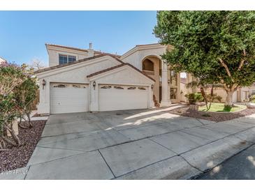 Elegant stucco home featuring a three-car garage and a beautiful arched entryway with a balcony at 1449 W Commerce Ave, Gilbert, AZ 85233