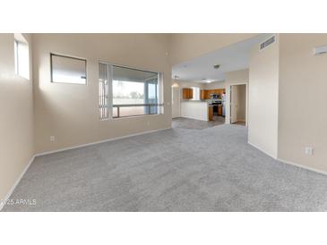 Spacious living room featuring neutral carpeting, an open floorplan, and lots of natural light at 4234 S 62Nd Ln, Phoenix, AZ 85043
