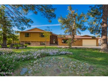 Charming home featuring a well-manicured lawn, mature trees, and colorful flower beds at 4612 W Waltann W Ln, Glendale, AZ 85306