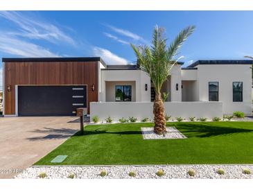 Beautiful modern home featuring a well-manicured lawn, stylish landscaping, and a sleek black garage door at 7325 E Virginia Ave, Scottsdale, AZ 85257