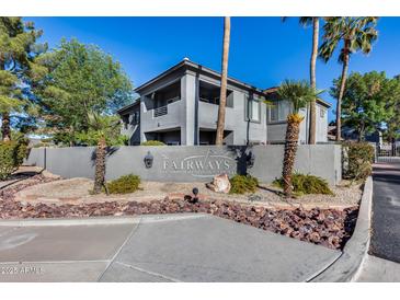 Elegant multi-story condominium featuring well-maintained landscaping with palm trees and a decorative stone perimeter wall at 7401 W Arrowhead Clubhouse Dr # 2007, Glendale, AZ 85308