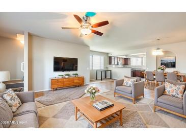Open-concept living room with comfortable seating, ceiling fan, and hardwood floors. Includes a view to the kitchen and dining area at 900 S 94Th St # 1204, Chandler, AZ 85224