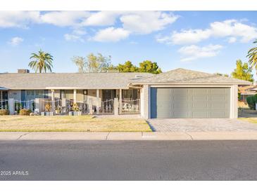 Charming home featuring a low-maintenance front yard, covered porch, and attached garage for convenient parking at 10326 W Kingswood Cir, Sun City, AZ 85351