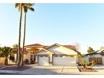 Charming single-story home featuring a three-car garage, tile roof, and lush palm trees at 1490 W Laurel Ave, Gilbert, AZ 85233