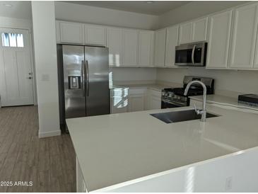 Modern kitchen features stainless steel appliances, white cabinetry, and a central island with a sink at 4330 N 94Th Ave, Phoenix, AZ 85037