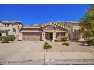 Charming single-story home featuring a well-manicured lawn, two-car garage and inviting entryway at 4552 E County Down Dr, Chandler, AZ 85249