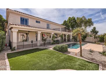 Inviting backyard with green lawn, pool, covered patio, and manicured landscaping at 1614 E Kathleen Rd, Phoenix, AZ 85022