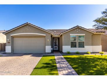 Charming single-story home featuring a well-manicured lawn, a brick driveway, and a two-car garage at 18735 W San Juan Ave, Litchfield Park, AZ 85340