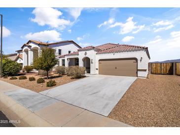 Charming single-story home with a well-maintained front yard, two car garage and terracotta colored roof tiles at 30382 W Vale Dr, Buckeye, AZ 85396