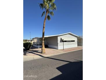 Cozy single story home with palm tree, manicured gravel landscaping, and a covered porch at 10955 N 79Th N Ave # 34, Peoria, AZ 85345