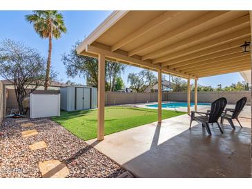 Covered patio with view of putting green, shed, lush landscape, and a private pool, creating an outdoor oasis at 1537 W Impala Ave, Mesa, AZ 85202