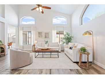 Bright living room featuring soaring ceilings, many windows, neutral decor, and wood-look flooring at 1728 E Barbarita Ave, Gilbert, AZ 85234