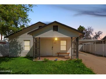 Charming single-story home with a covered front porch, well-maintained lawn, and covered parking at 2032 E Harvard St, Phoenix, AZ 85006