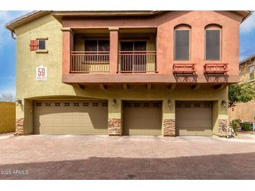 A three-car garage beneath a two-story condo with brick driveway at 2150 E Bell Rd # 1176, Phoenix, AZ 85022