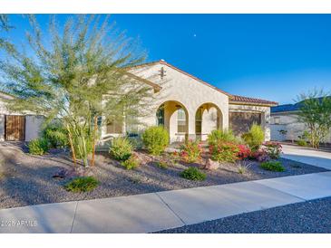 Charming single-story home featuring a desert landscape with colorful flowering bushes and a stucco exterior, with arched entryway at 5245 N 205Th Ln, Buckeye, AZ 85396