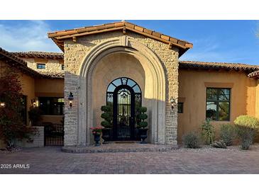 Stunning custom home features a unique stone archway entrance with iron door and lush landscaping at 6880 E Flat Iron Loop, Gold Canyon, AZ 85118