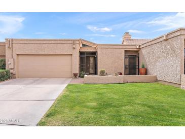 Charming single-story home featuring a manicured lawn, private drive, and desert landscaping at 7937 E Solano Dr, Scottsdale, AZ 85250