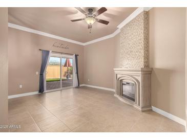 Living room features a ceiling fan, decorative fireplace, and a sliding glass door with access to the backyard at 13628 N 109Th Ave, Sun City, AZ 85351