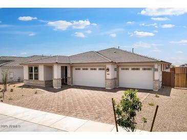 Charming single-story home featuring a three-car garage, neutral colors and brick accents at 16749 W Whispering Wind Dr, Surprise, AZ 85387