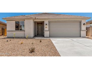 Charming single-story home showcasing desert landscaping, a gray garage door, and a tiled roof at 18347 W Monte Lindo Ln, Surprise, AZ 85387
