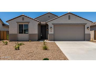 Charming single-story home featuring a neutral color scheme, desert landscaping, and an attached two-car garage at 18363 W Monte Lindo Ln, Surprise, AZ 85387
