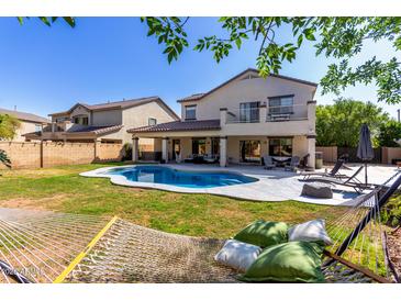 Inviting backyard features a sparkling pool, covered patio, lounge chairs, and a relaxing hammock with green pillows at 11121 N 165Th Ave, Surprise, AZ 85388