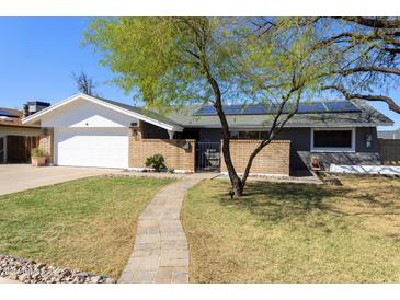 Charming home with a well-manicured lawn, brick accents, and inviting walkway to the front door at 15218 N 37Th Ave, Phoenix, AZ 85053