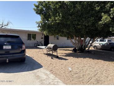 Modest home featuring a sandy front yard with mature shade tree, grill, and driveway parking at 6018 N 32Nd Ave, Phoenix, AZ 85017