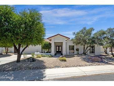 Charming single-story home featuring desert landscaping, mature trees, and a stucco exterior at 10013 N 106Th Pl, Scottsdale, AZ 85258