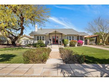 Charming single-story home with lush landscaping and a welcoming red front door at 144 W Palm Ln, Phoenix, AZ 85003