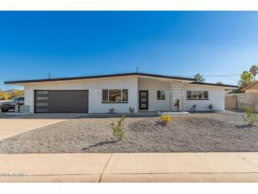Charming single-story home featuring a modern design with gravel landscaping and a gray accent garage door at 3939 E Sahuaro Dr, Phoenix, AZ 85028