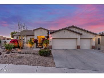 Charming single-story home featuring a 3-car garage and desert landscaping at dusk at 6022 W Fetlock Trl, Phoenix, AZ 85083