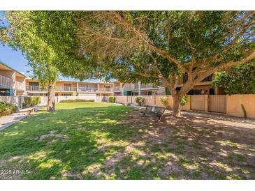 Inviting community lawn area with mature trees and seating, perfect for relaxing outdoors at 6565 N 19Th Ave # 59, Phoenix, AZ 85015