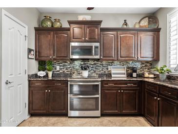 Modern kitchen boasts granite countertops, dark wood cabinets, stainless steel appliances, and mosaic backsplash at 2512 E Vermont Dr, Gilbert, AZ 85295