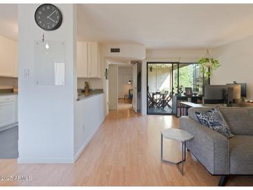 Bright living room boasts wood floors, a neutral color palette, and a sliding door leading to a patio at 4950 N Miller Rd # 248, Scottsdale, AZ 85251