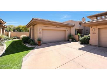 Spacious two-car garage and driveway with a well-manicured lawn and desert landscaping at 15240 N Clubgate Dr # 162, Scottsdale, AZ 85254